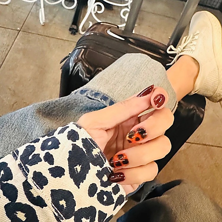 Uñas cortas en color vino con dos uñas en animal print tipo carey naranja y negro