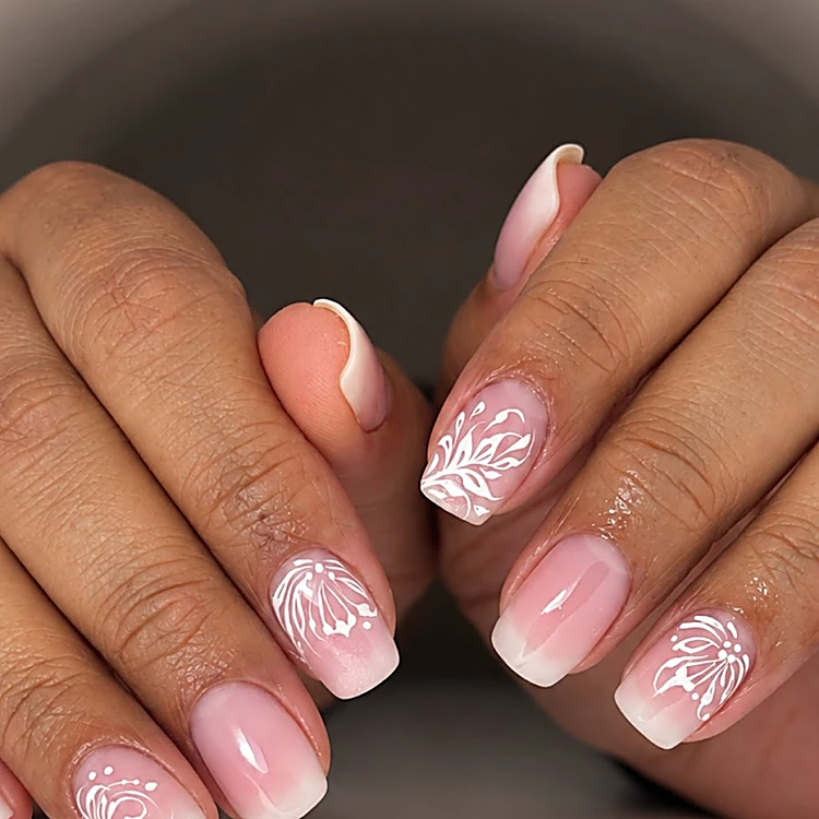Uñas cortas con degradado rosa a blanco y detalles de encaje blanco pintado