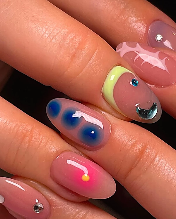 Uñas almendra rosa translúcido con gotas azules difuminadas, punto neón amarillo y rosa, media luna lima y piedras de strass