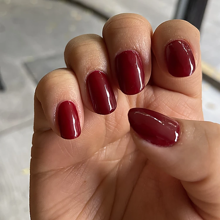 Mano con uñas cortas en rojo cereza brillante, color liso